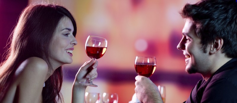 Young happy amorous couple celebrating with red wine at restaura
